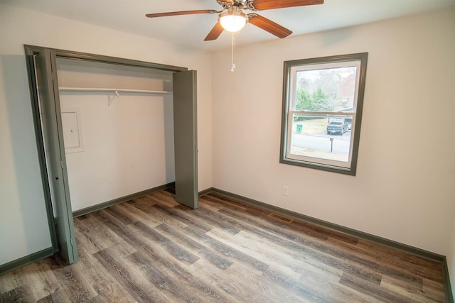 unfurnished bedroom featuring visible vents, baseboards, a ceiling fan, wood finished floors, and a closet