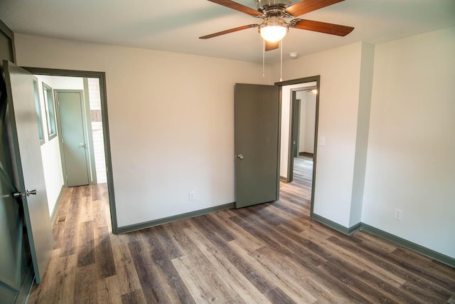 unfurnished bedroom featuring a ceiling fan, visible vents, baseboards, and wood finished floors