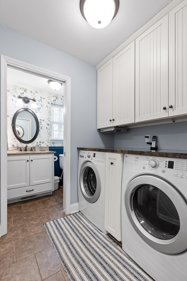 clothes washing area with cabinet space, stone finish flooring, a sink, separate washer and dryer, and baseboards