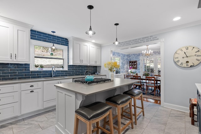 kitchen featuring crown molding, white cabinets, a sink, and a center island