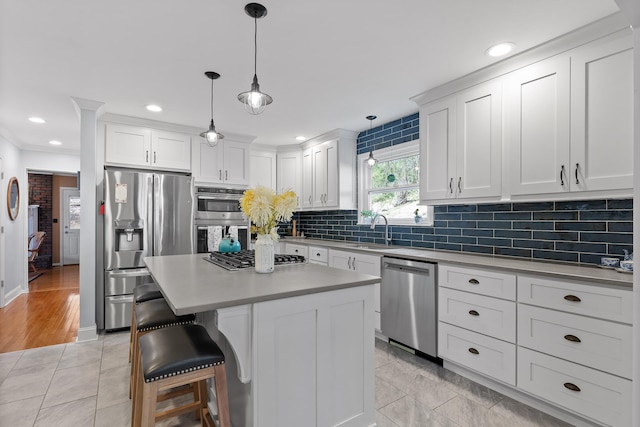 kitchen featuring stainless steel appliances, a sink, white cabinets, light countertops, and tasteful backsplash