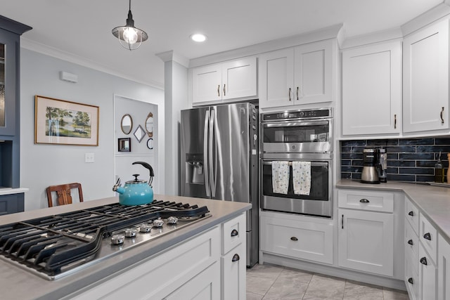 kitchen with white cabinets, appliances with stainless steel finishes, ornamental molding, light countertops, and backsplash