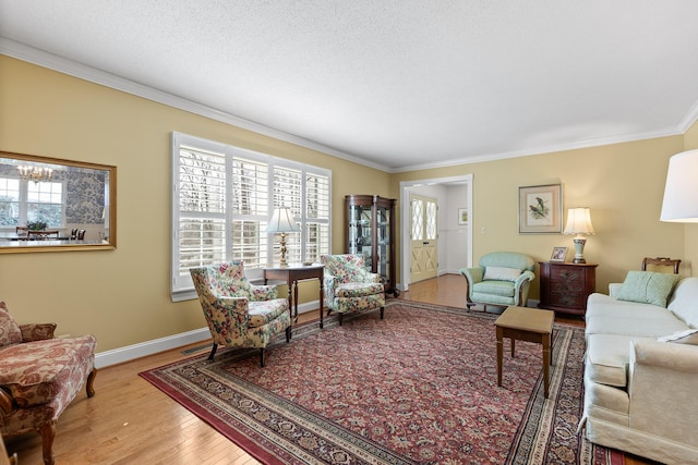 living room featuring crown molding, visible vents, a textured ceiling, wood finished floors, and baseboards