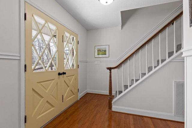 entryway featuring baseboards, stairs, visible vents, and wood finished floors