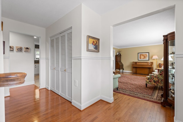 hall with light wood-style flooring and baseboards