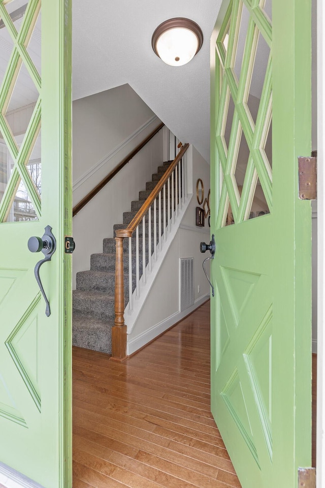 entrance foyer featuring stairs, visible vents, and wood finished floors