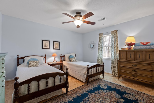 bedroom with a textured ceiling, a ceiling fan, visible vents, and baseboards