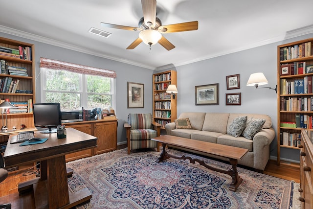 home office with ceiling fan, visible vents, baseboards, light wood-type flooring, and crown molding