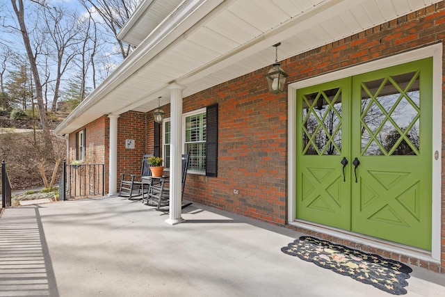 entrance to property with a porch and brick siding