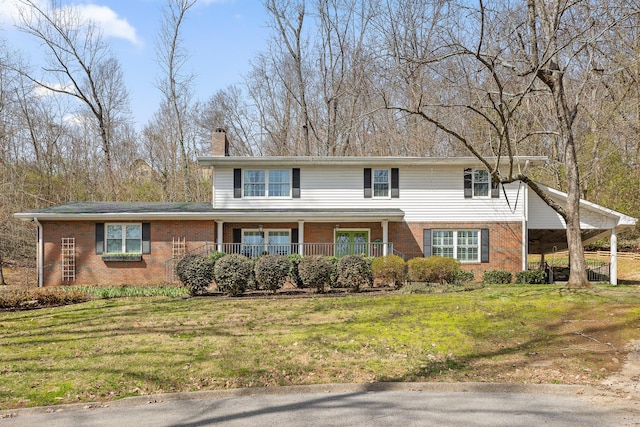 traditional-style home with covered porch, brick siding, and a front yard