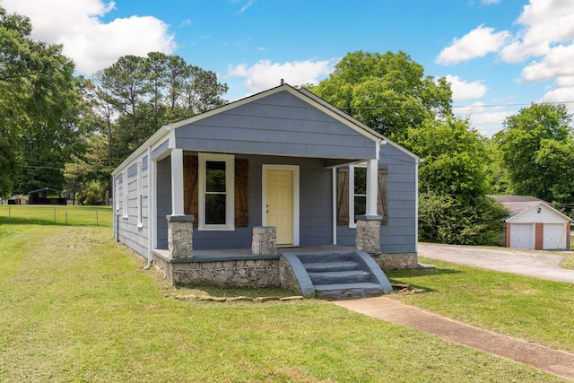 view of front facade featuring fence, a front lawn, a porch, and an outbuilding