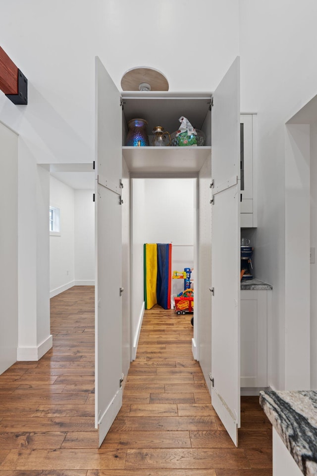 corridor with baseboards and light wood-style floors