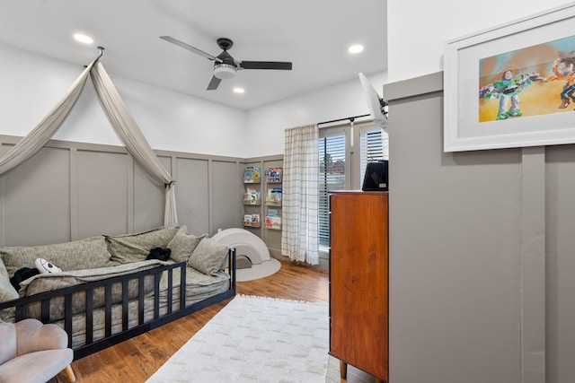 bedroom featuring recessed lighting, a wainscoted wall, a decorative wall, and wood finished floors