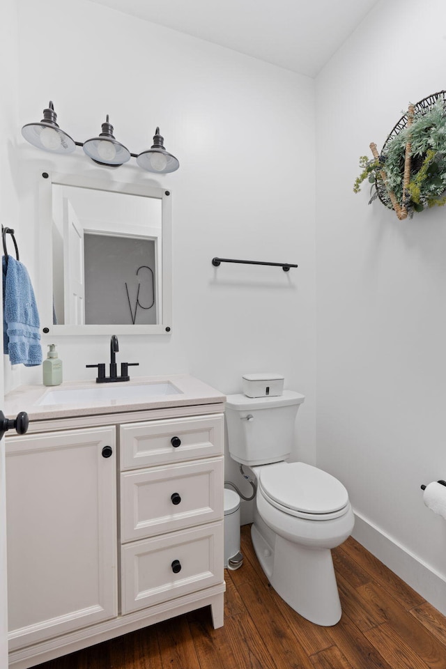 bathroom with wood finished floors, vanity, toilet, and baseboards