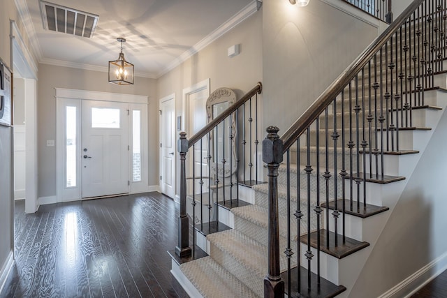 foyer with ornamental molding, wood finished floors, visible vents, and baseboards