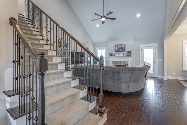 living area featuring plenty of natural light, high vaulted ceiling, a brick fireplace, and wood finished floors