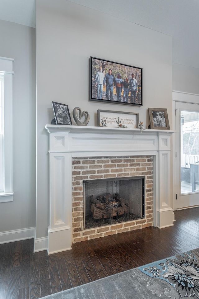 interior details with a brick fireplace, baseboards, and wood finished floors