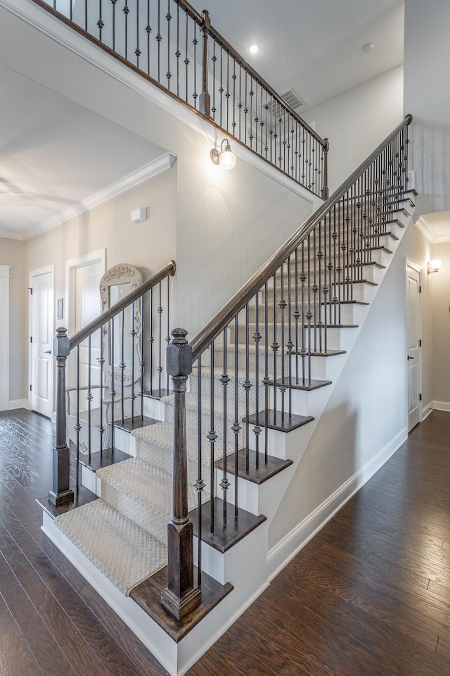 stairway featuring baseboards, crown molding, and hardwood / wood-style floors