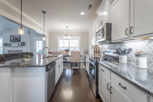 kitchen with stainless steel appliances, a sink, visible vents, decorative backsplash, and crown molding