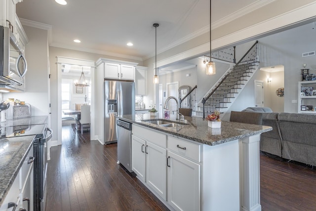 kitchen featuring appliances with stainless steel finishes, open floor plan, dark wood-style flooring, crown molding, and a sink