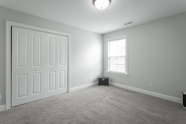 unfurnished bedroom with a closet, carpet, visible vents, and baseboards