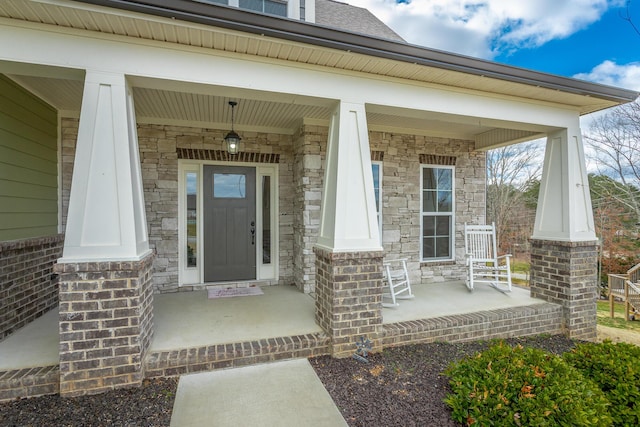 doorway to property with a porch and brick siding