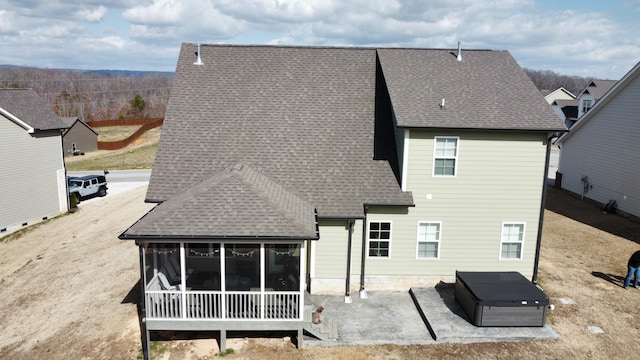 rear view of house featuring a shingled roof, a sunroom, and a patio area