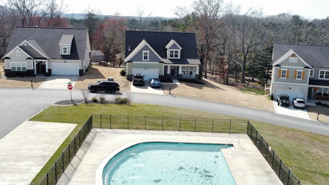 view of swimming pool featuring a view of trees, fence, a fenced in pool, and a yard