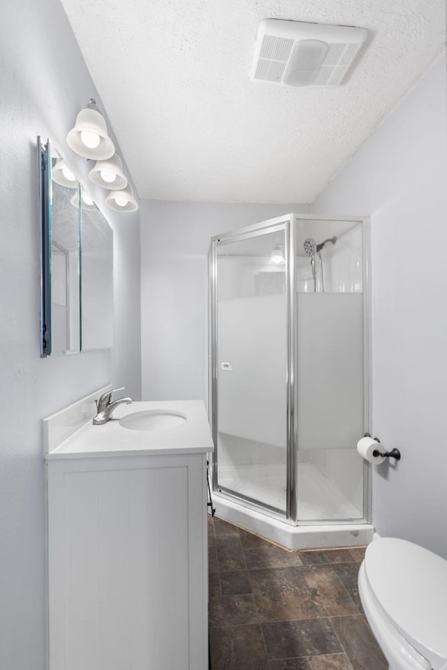 bathroom with vanity, a shower stall, visible vents, and a textured ceiling