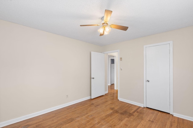 unfurnished bedroom with ceiling fan, baseboards, a textured ceiling, and light wood-style flooring