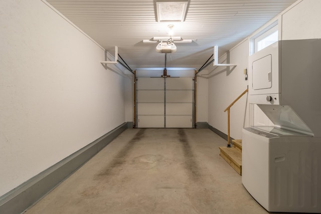 garage with a garage door opener, stacked washer / dryer, and baseboards