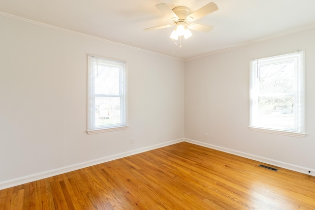 empty room featuring a wealth of natural light, visible vents, crown molding, and light wood-style flooring