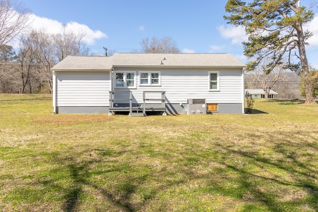 back of house with central air condition unit, a shingled roof, and a yard