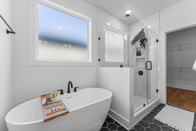 bathroom featuring baseboards, a freestanding tub, a stall shower, a spacious closet, and tile patterned floors