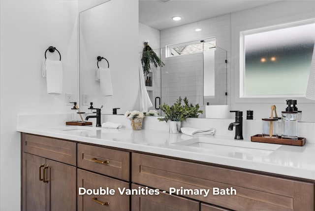 full bathroom with double vanity, a shower stall, and a sink