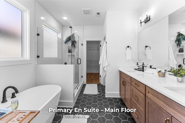 bathroom with visible vents, a stall shower, a sink, double vanity, and a freestanding bath