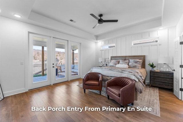 bedroom featuring hardwood / wood-style floors, baseboards, visible vents, access to exterior, and a raised ceiling