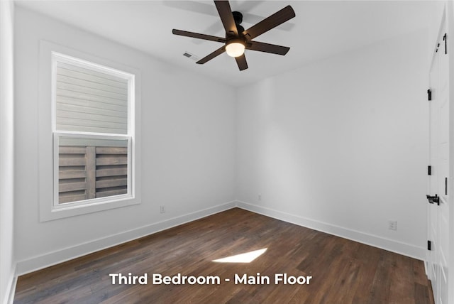 spare room with baseboards, dark wood-type flooring, and ceiling fan