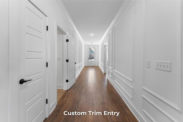 hallway featuring dark wood finished floors and a decorative wall