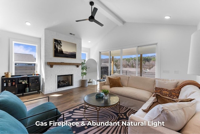 living area with visible vents, vaulted ceiling with beams, wood finished floors, and plenty of natural light