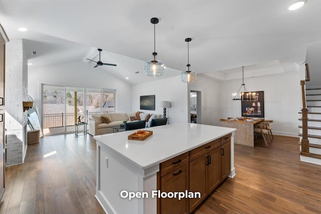 kitchen with decorative light fixtures, a kitchen island, dark wood-style floors, and a ceiling fan