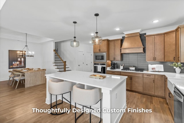 kitchen featuring a kitchen bar, custom range hood, wood finished floors, appliances with stainless steel finishes, and decorative backsplash