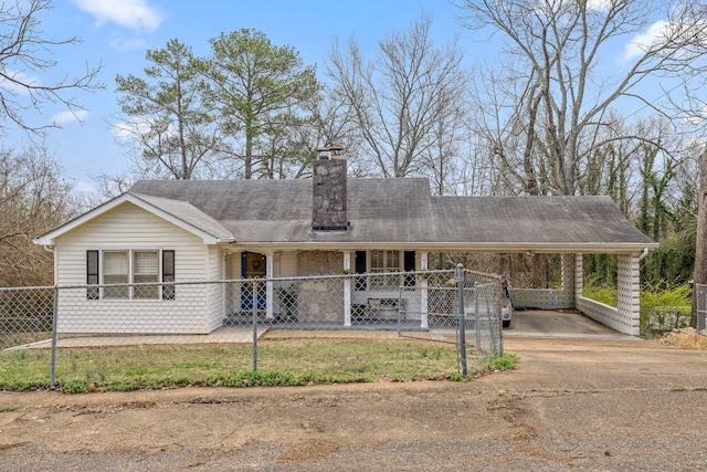 view of front of house featuring a carport, driveway, a fenced front yard, and a chimney