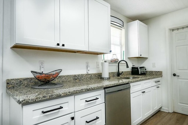 kitchen featuring light stone counters, wood finished floors, a sink, white cabinetry, and dishwasher