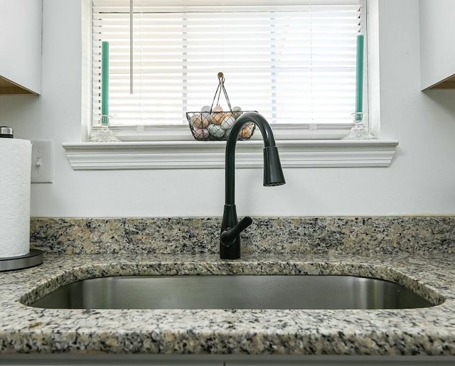 interior details with light stone counters and a sink