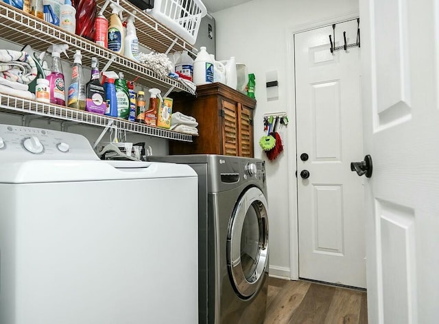 clothes washing area featuring laundry area, wood finished floors, and washing machine and clothes dryer