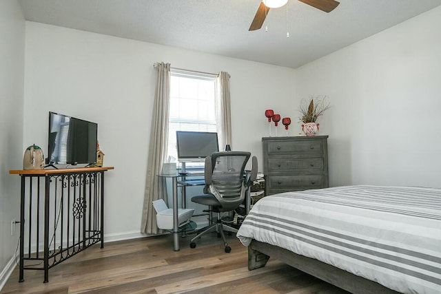 bedroom with ceiling fan, wood finished floors, and baseboards