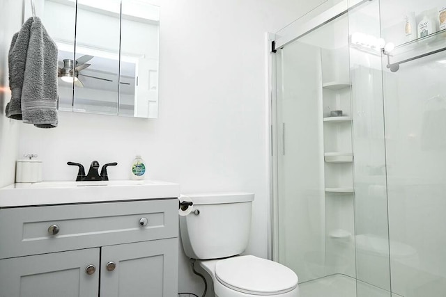 bathroom featuring toilet, a shower stall, and vanity