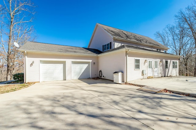 view of side of home featuring concrete driveway and an attached garage