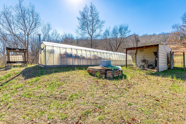 view of yard featuring a greenhouse and an outdoor structure